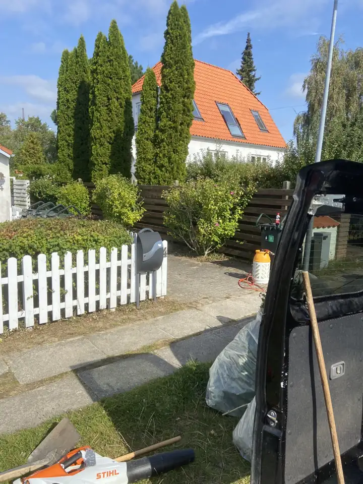 Forhave med hvidt stakit og klippet hæk